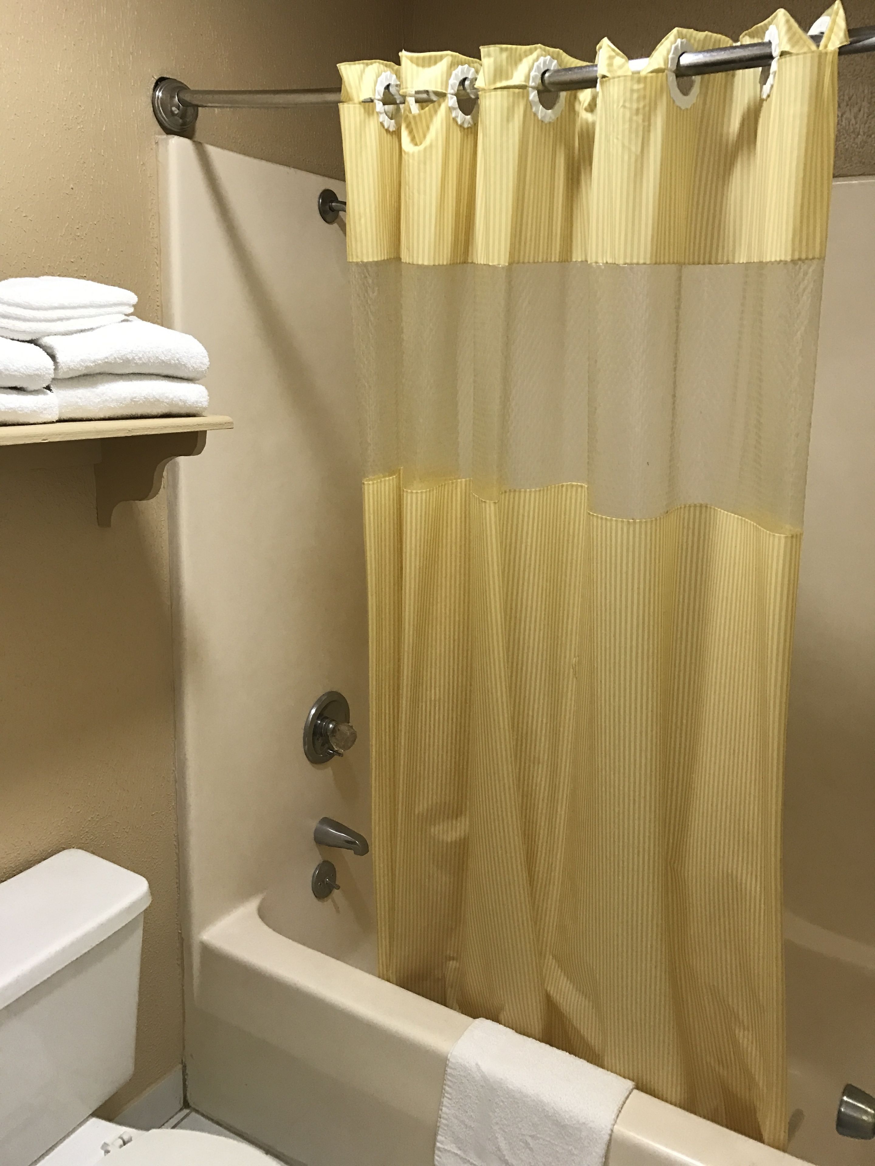 A bathroom with a bathtub, a toilet, and a towel rack with folded towels.