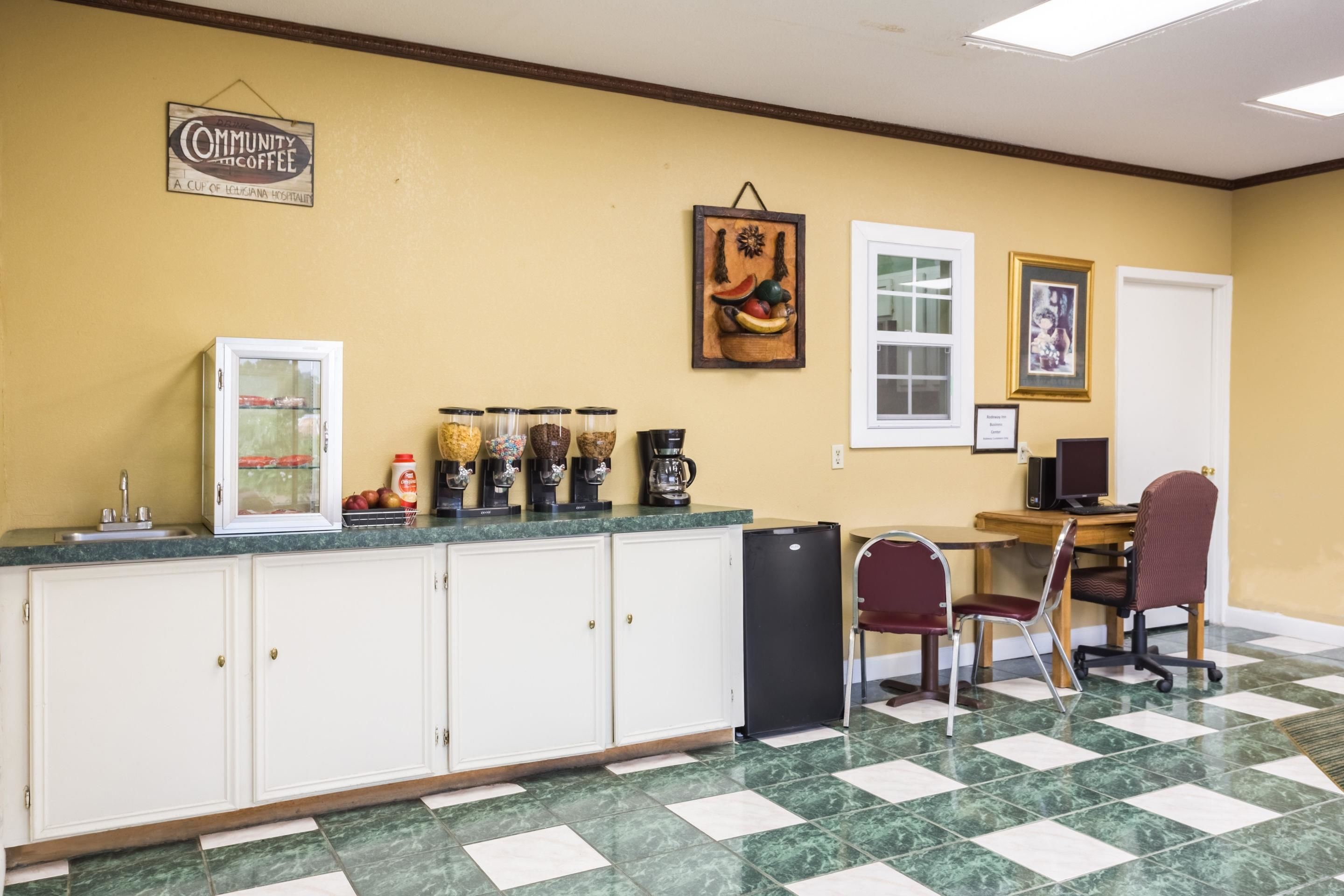 Una cocina con piso de mármol, refrigerador, estación de café y comedor con sillas y mesa.