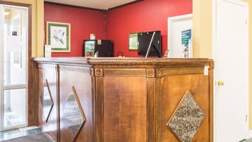 A reception desk with a red wall, a white door, and a small refrigerator.