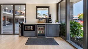 Una cocina moderna con microondas integrado, cafetera y dispensador de bebidas.