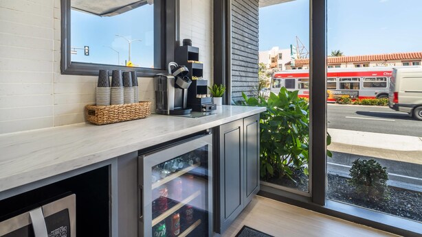 Una cocina moderna con cafetera, refrigerador y ventana con vista a la calle.