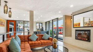 Un moderno vestíbulo de hotel con un amplio sofá modular, una mesa de centro de vidrio y una chimenea.
