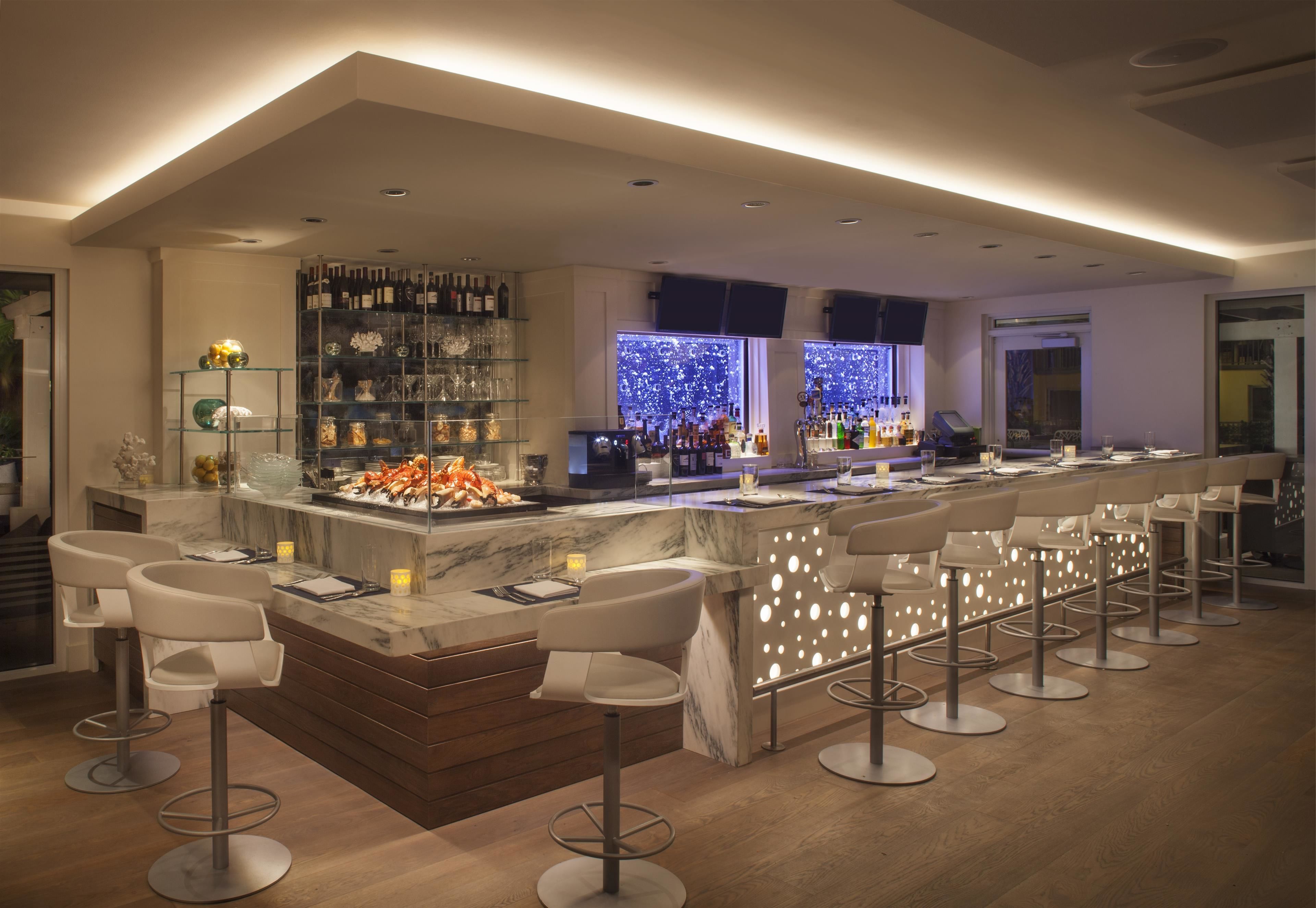 A modern bar area with a marble countertop, multiple bar stools, and a wine rack.