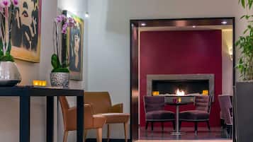 A modern lounge area with a fireplace, comfortable seating, and decorative elements like orchids and artwork.
