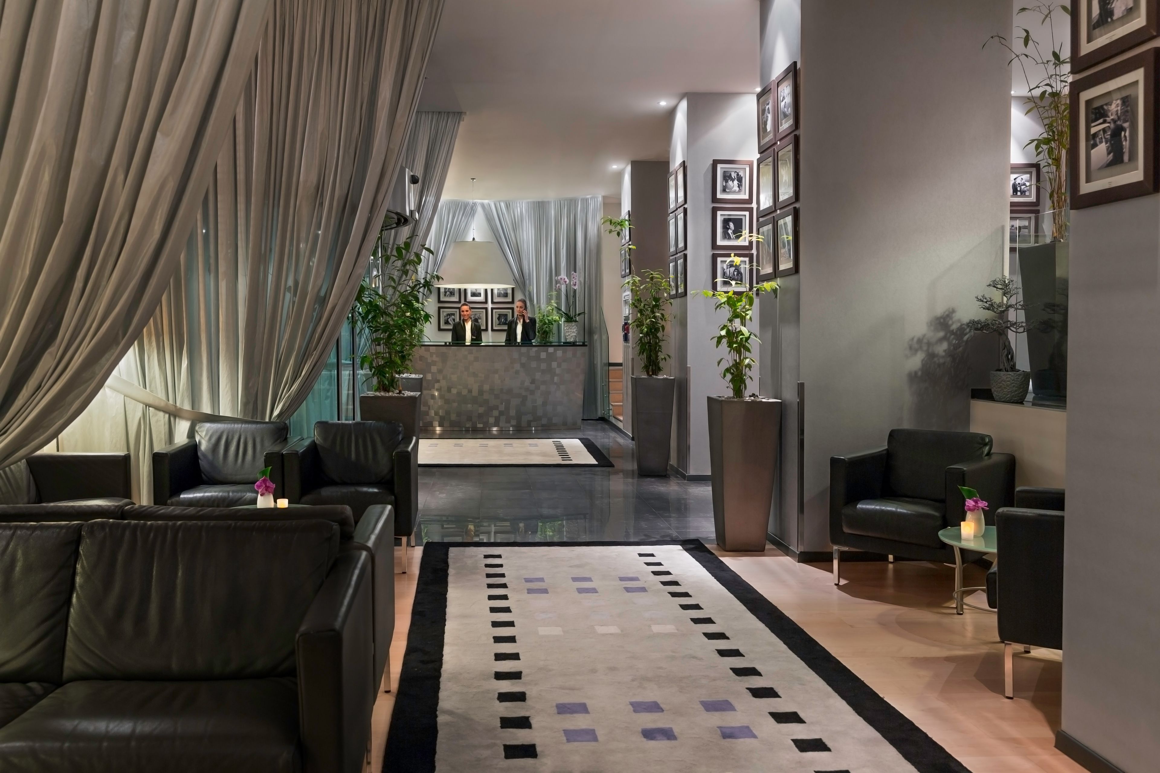 Eine moderne Hotelhalle mit Ledersofas, einem Empfangstresen und gerahmten Bildern an den Wänden.