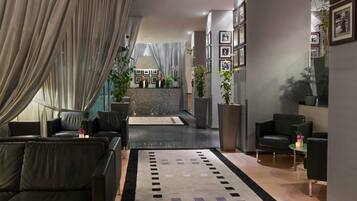Eine moderne Hotelhalle mit Ledersofas, einem Empfangstresen und gerahmten Bildern an den Wänden.
