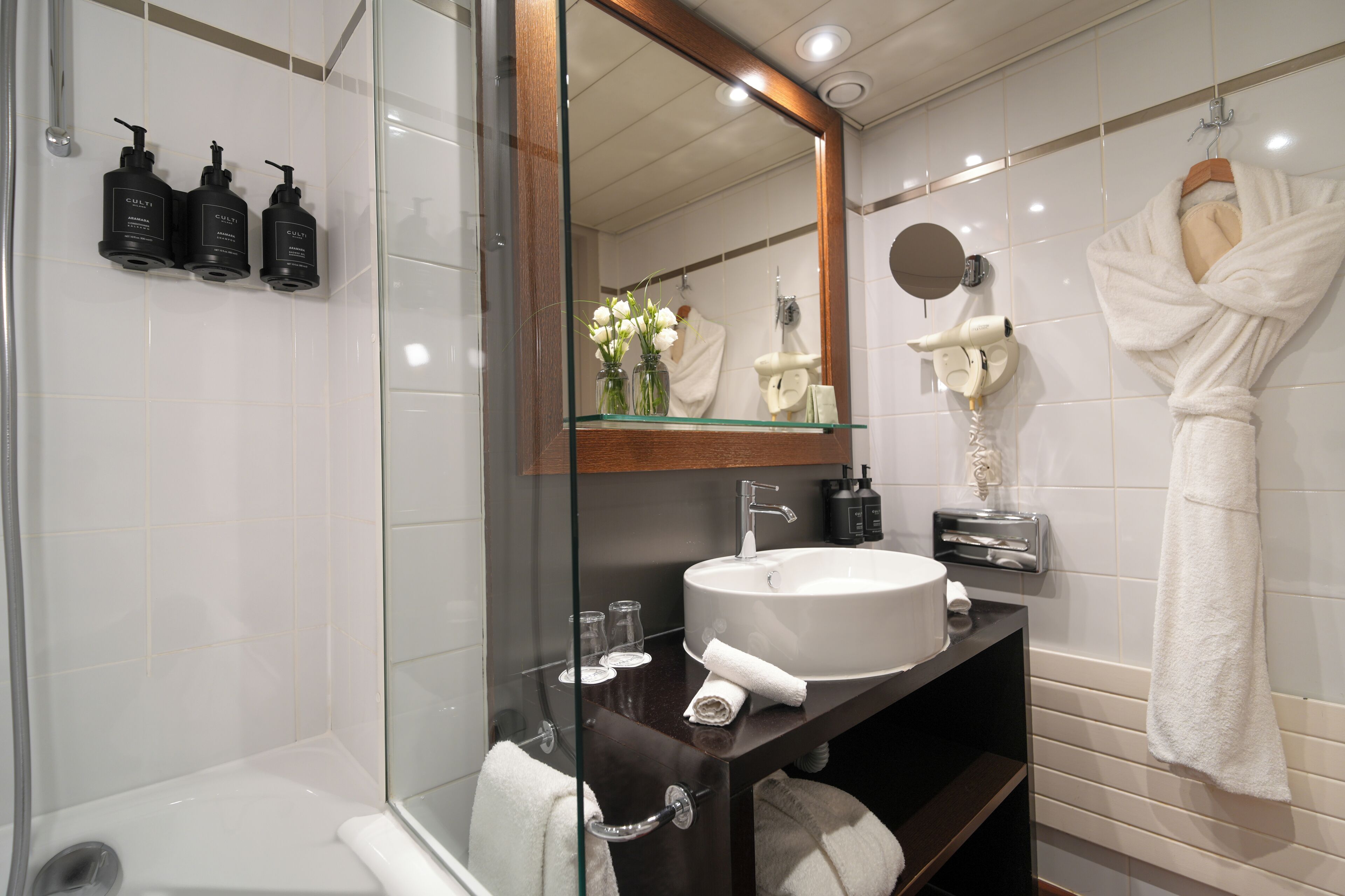 A modern bathroom with a glass shower enclosure, a white sink, and a mirror above the vanity.