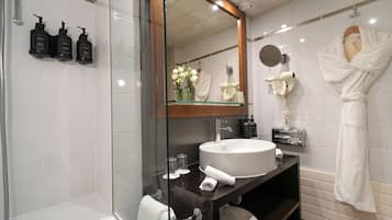 A modern bathroom with a glass shower enclosure, a white sink, and a mirror above the vanity.