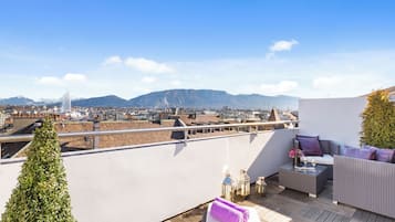 A rooftop terrace with a view of a cityscape and mountains.