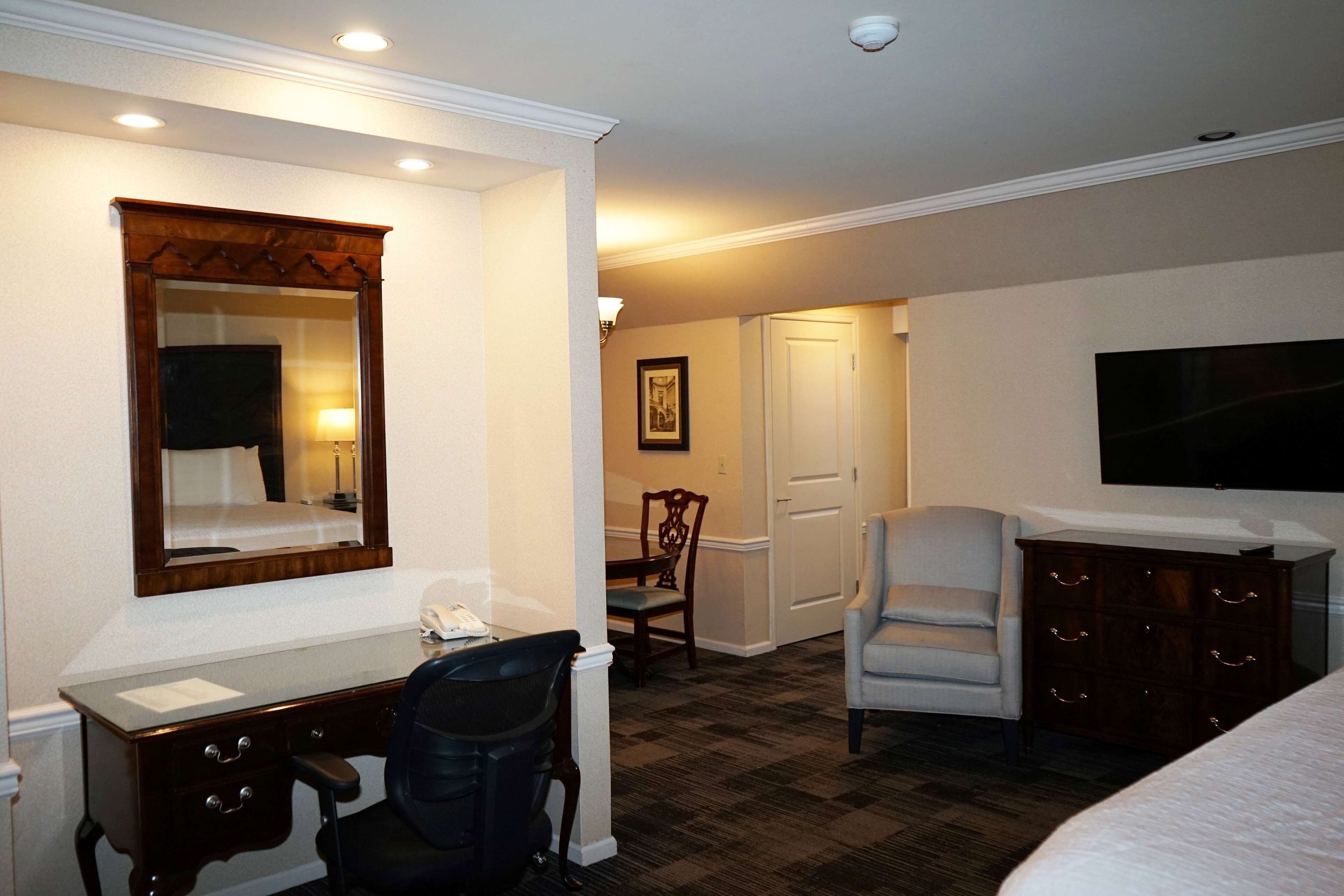 Habitación de hotel con escritorio, silla, cómoda y televisor.