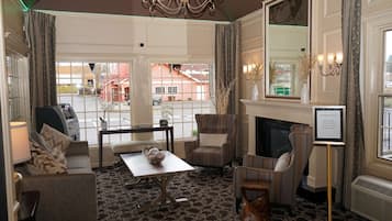 Een hotelkamer met een open haard, zithoek en uitzicht op de straat.