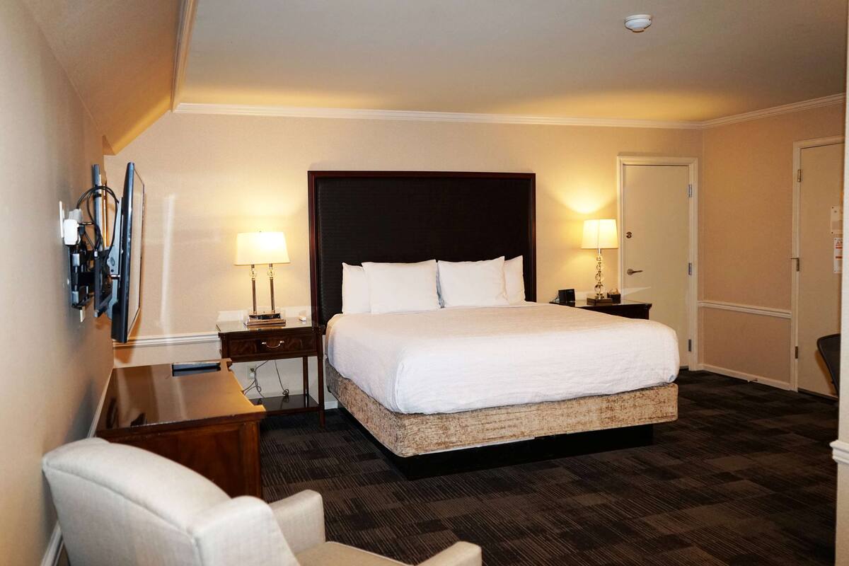 A hotel room with a large bed, two bedside tables, a desk, and a chair.