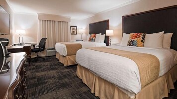 Habitación de hotel con dos camas, un escritorio, una silla y un televisor.