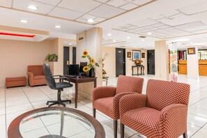 A reception area with checkered chairs, a desk with a computer, and a glass table. - Quality Inn & Suites Orlando Airport (Orlando)