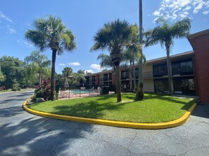 A hotel with a pool, surrounded by palm trees and a well-maintained lawn. - Quality Inn & Suites Orlando Airport (Orlando)
