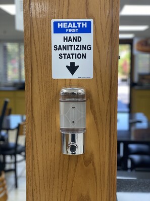 A hand sanitizing station with a sign above it. - Quality Inn & Suites Orlando Airport (Orlando)