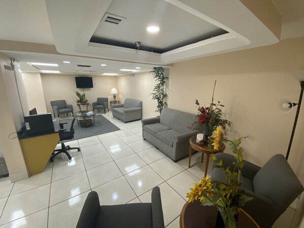 A modern waiting area with a reception desk, several seating options, and a flat-screen TV mounted on the wall. - Quality Inn & Suites Orlando Airport (Orlando)