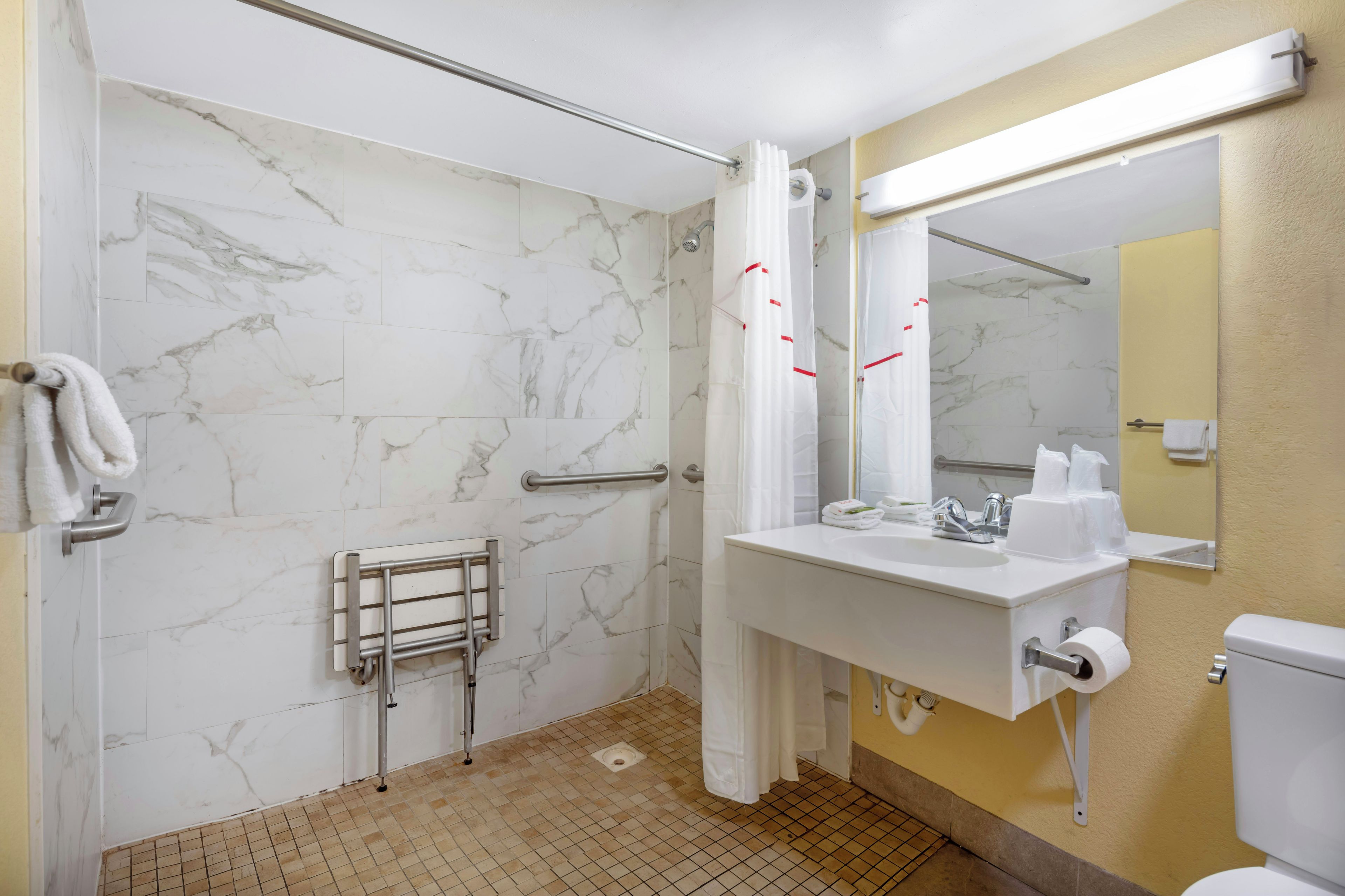 Un baño con ducha, inodoro, lavamanos y toallero.