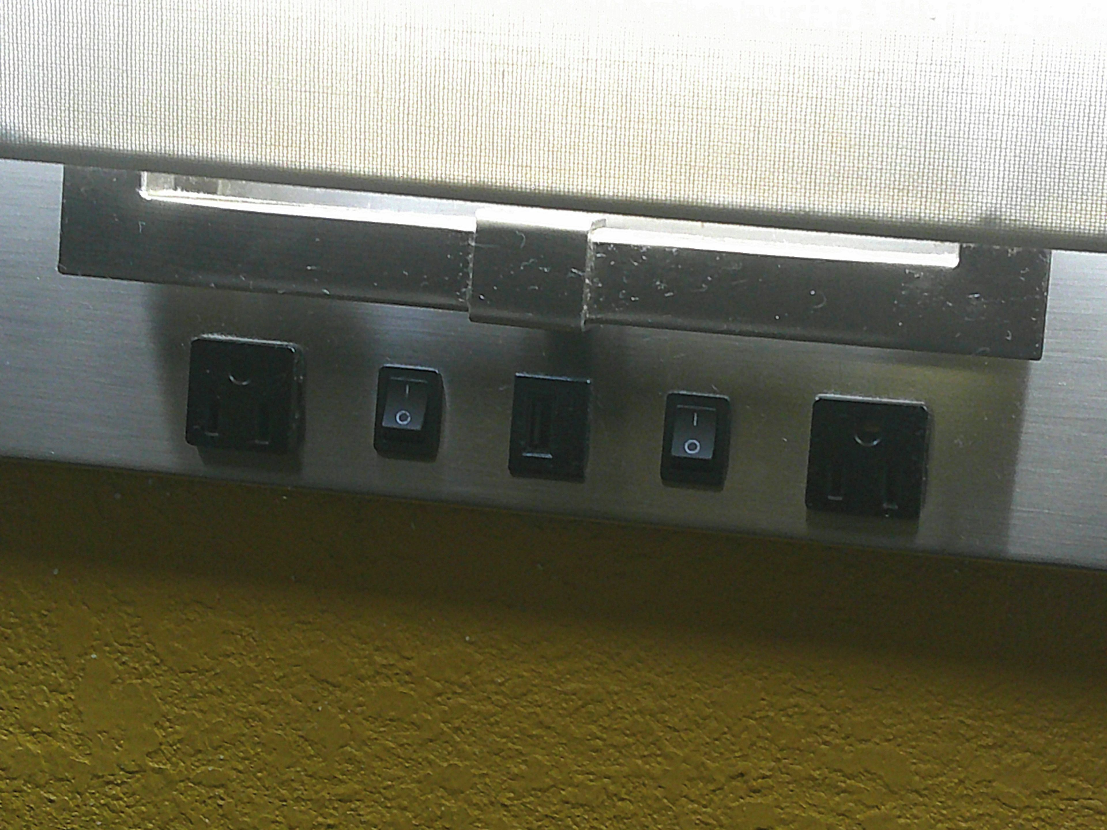 A wall-mounted electrical panel with four switches.