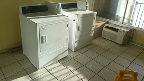 A laundry room with two stacked washers and dryers, a window with blinds, and a sign stating "NO REFUNDS." -  Red Roof Inn Hampton Coliseum (Hampton)