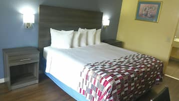 Una habitación de hotel con una cama, dos mesitas de noche, una lámpara de pared y un cuadro.