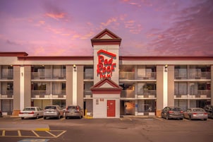 Un hotel de varios pisos con un llamativo letrero rojo que dice 'Red Roof Inn'.