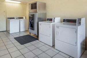 Un cuarto de lavandería con cuatro lavadoras y secadoras, un dispensador de agua y un panel de control.