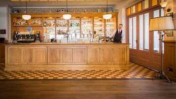 Een bar met houten kasten, een geruit vloertje en een bartender.