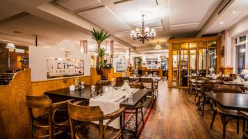 A restaurant with wooden furniture, a chandelier, and a red carpet.
