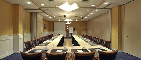 A conference room with a long table, chairs, and a projector screen at the front.