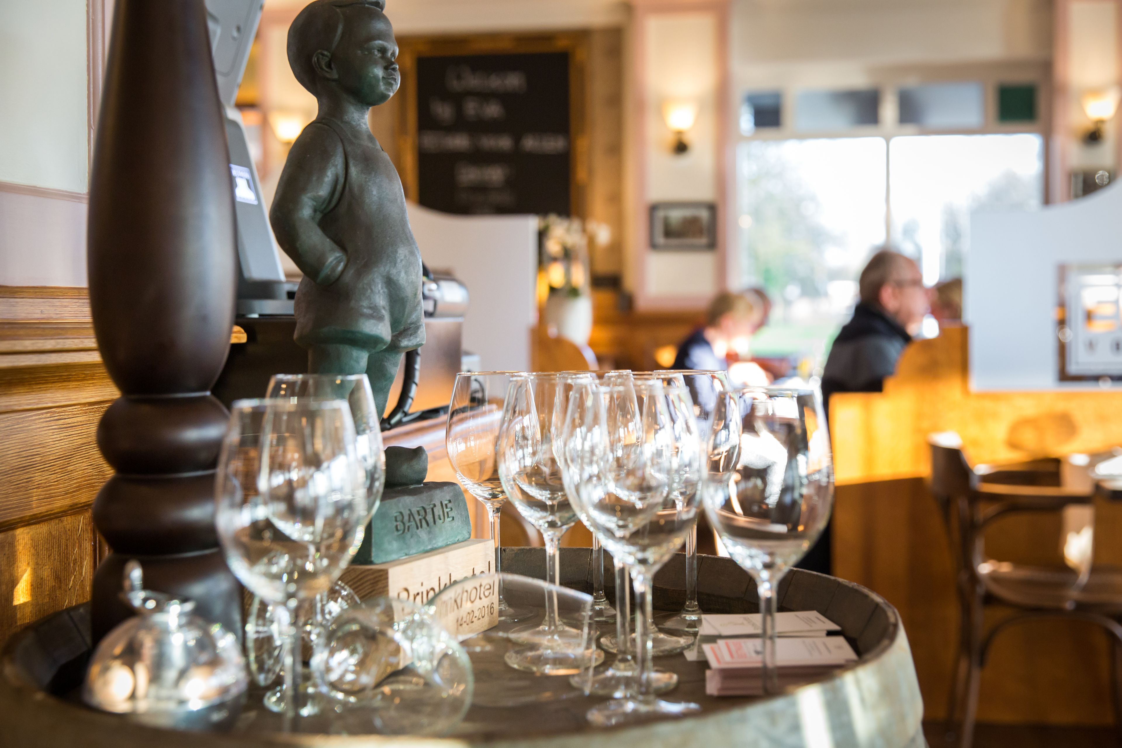 Una zona de bar con una estatua, varios vasos de vino y un cartel que indica la existencia de un minibar.