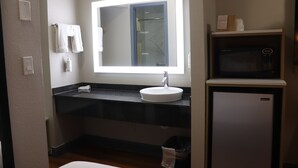 Un bagno con lavandino, specchio, porta asciugamani e forno a microonde.