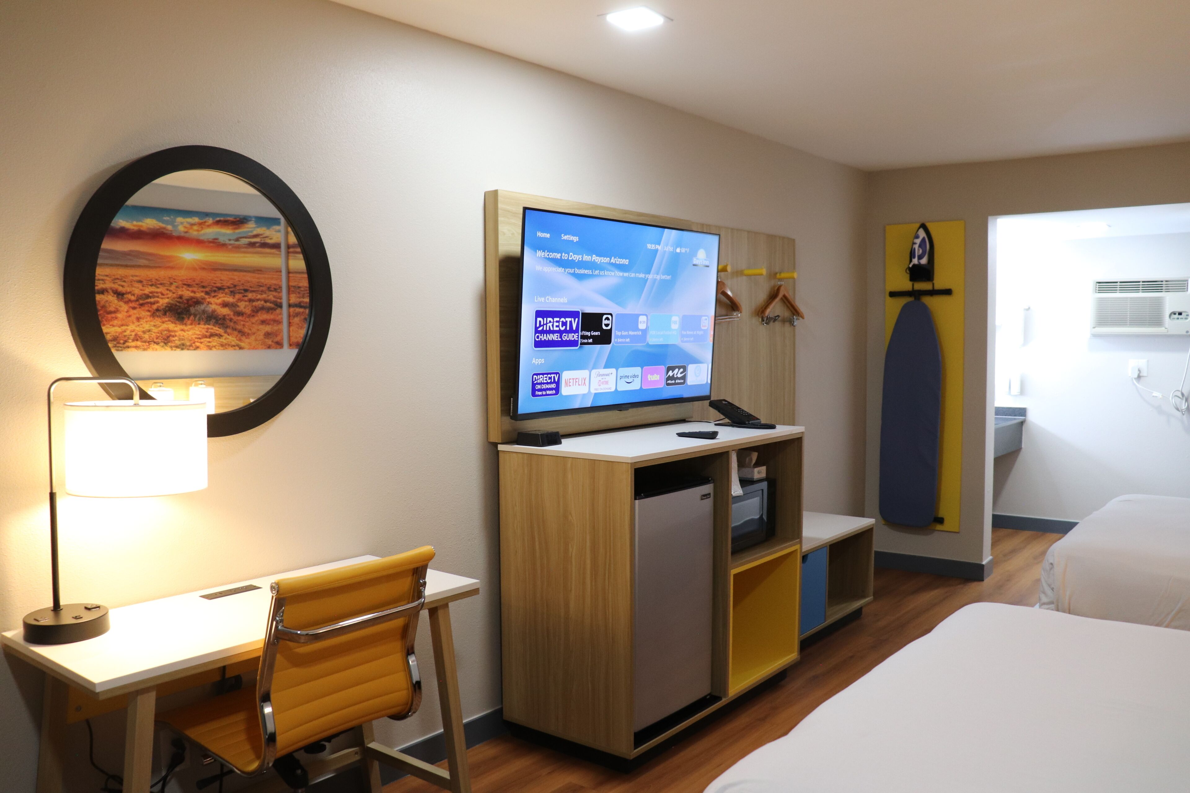 Une chambre d’hôtel équipée d’un bureau, d’une chaise, d’un lit, d’une télévision et offrant une vue sur l’extérieur.