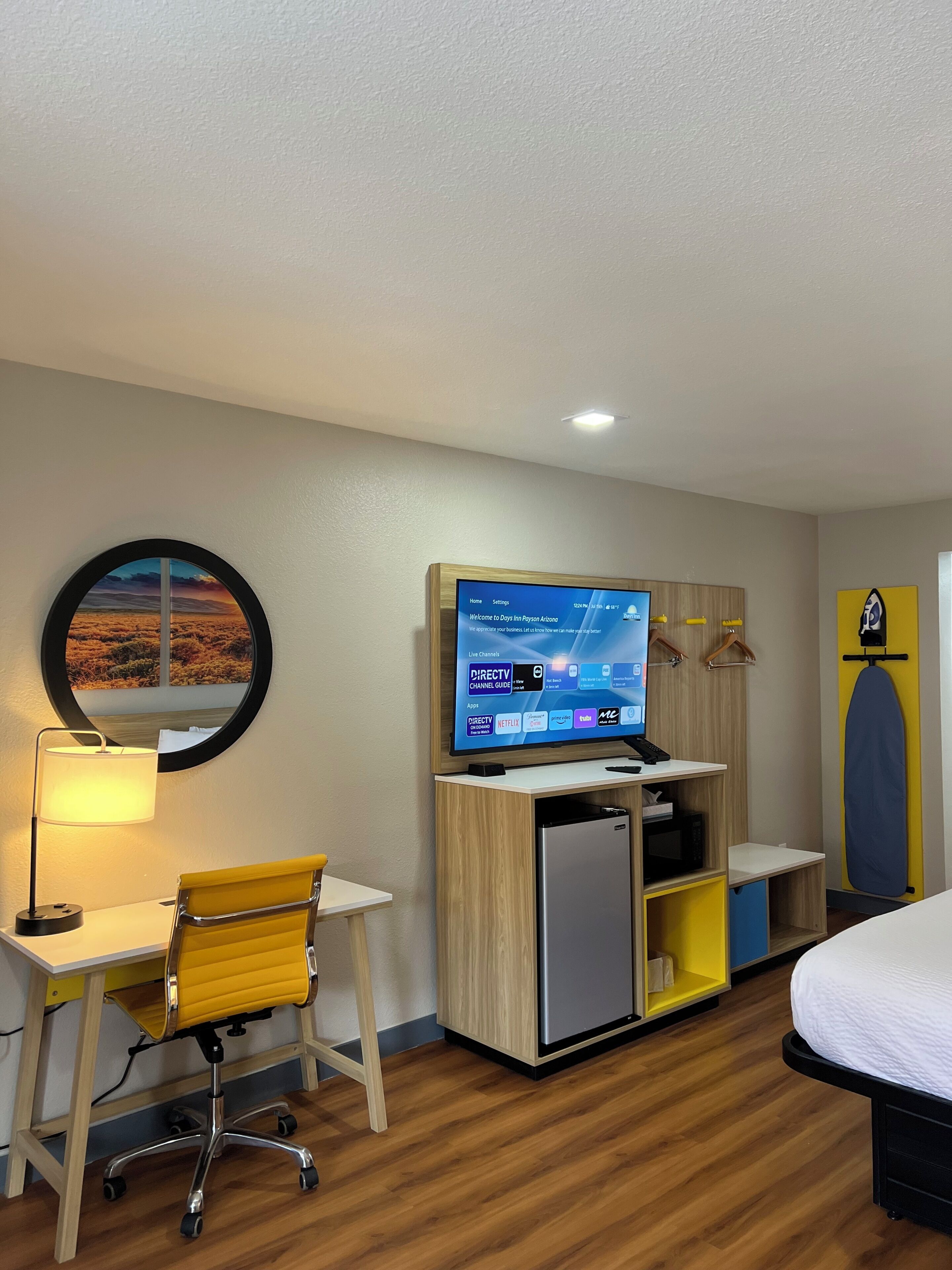 Une chambre d’hôtel équipée d’un bureau, d’une chaise, d’un lit, d’une télévision et offrant une vue sur un paysage désertique.