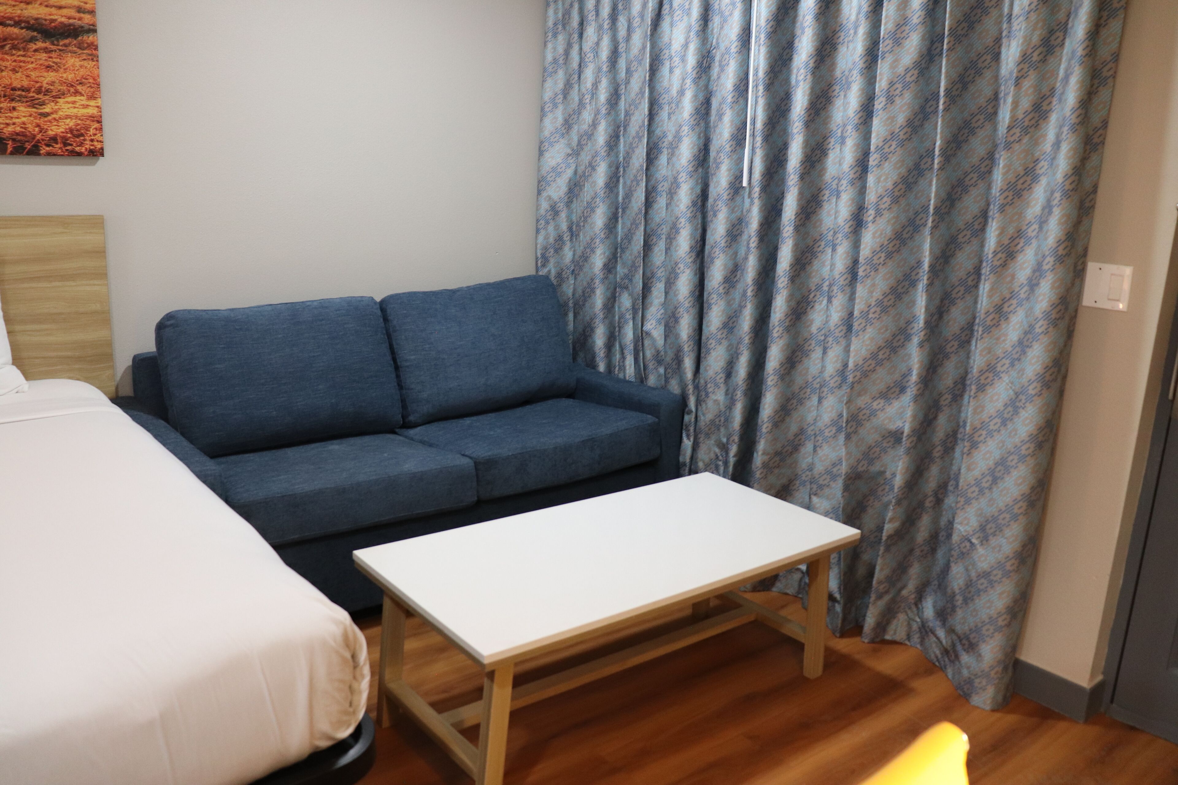 Una habitación con una cama, un sofá azul y una mesa blanca.