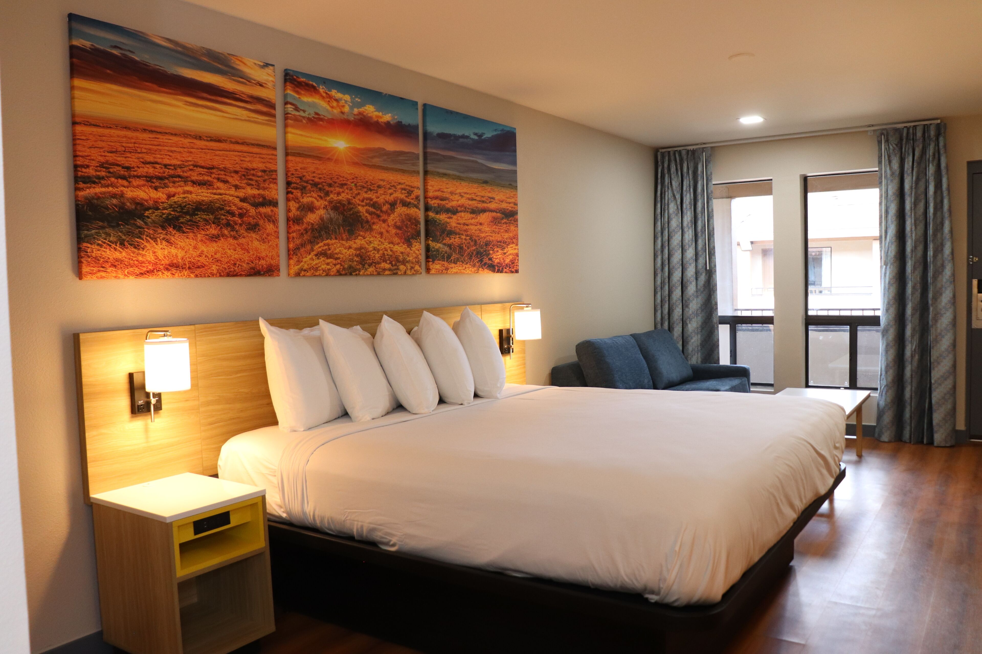 A hotel room with a large bed, bedside tables, a desk, and a view of the outside.