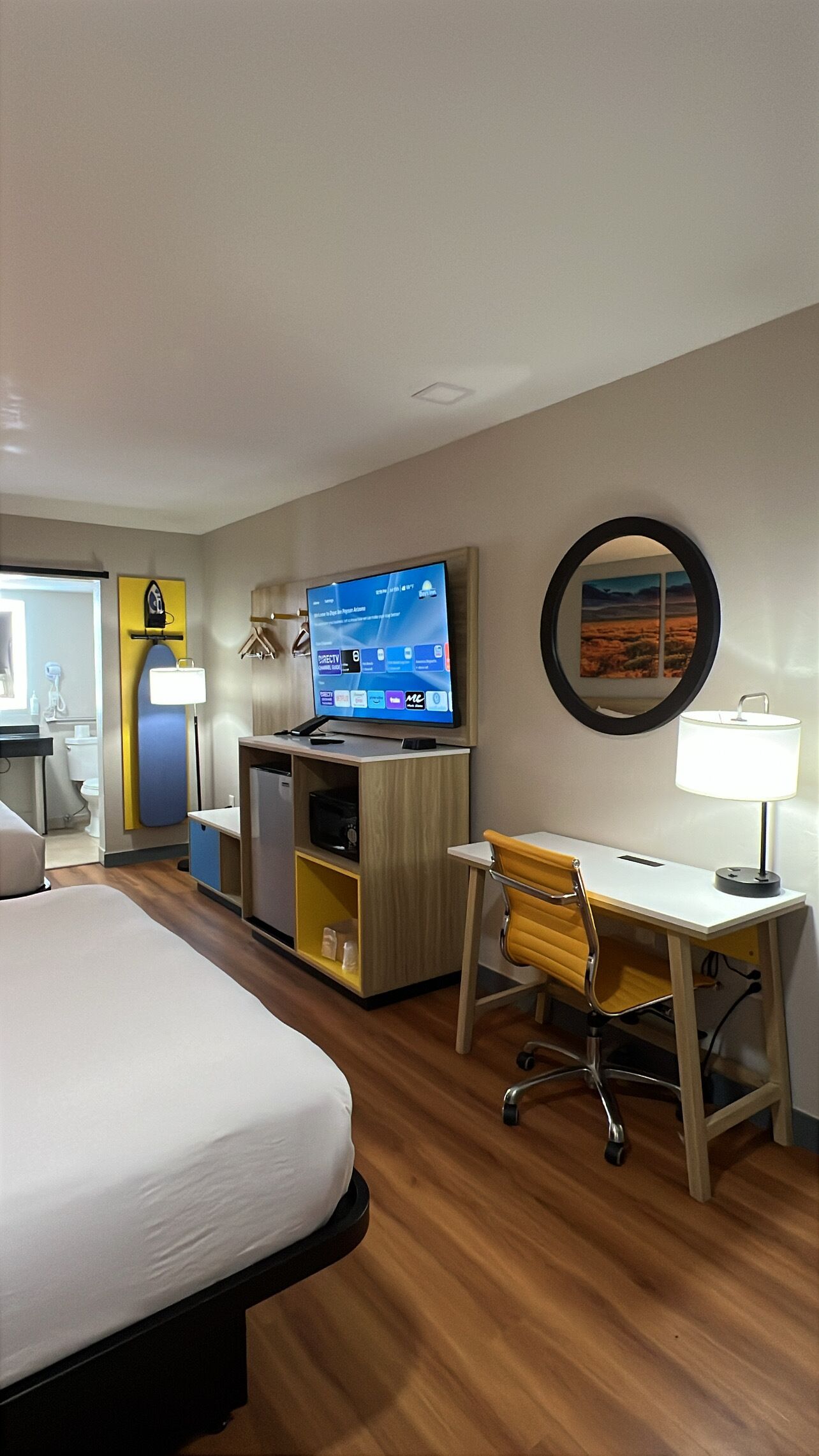 Una habitación de hotel con cama, escritorio, silla, televisor y baño.