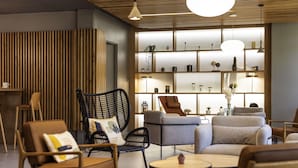 A modern lounge area with comfortable seating, a wooden slatted wall, and a well-lit display of decorative items. - Novotel Bordeaux Centre Gare Saint Jean (Bordeaux)
