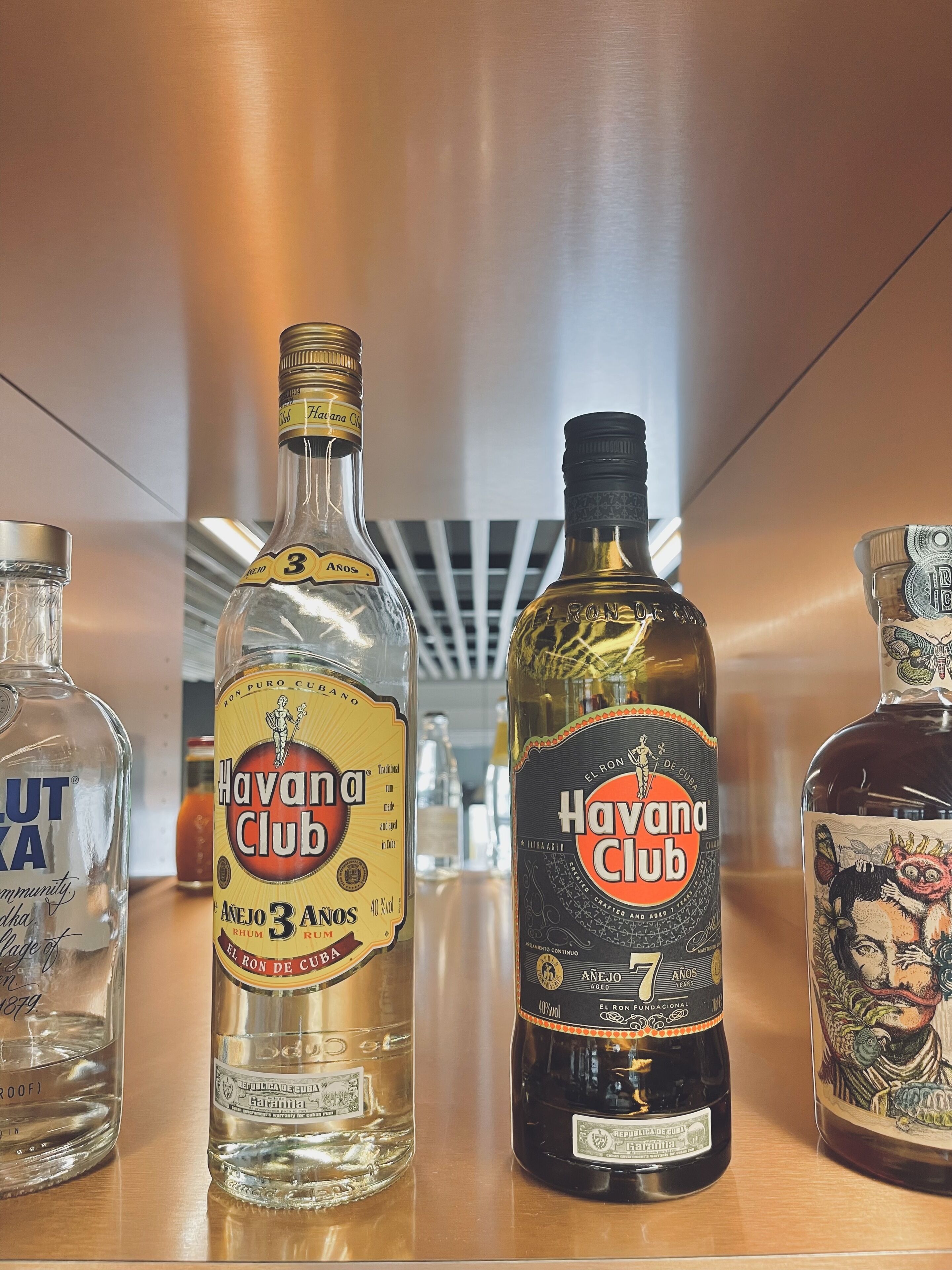 Drei Flaschen Havana Club Rum auf einem Holzboden.