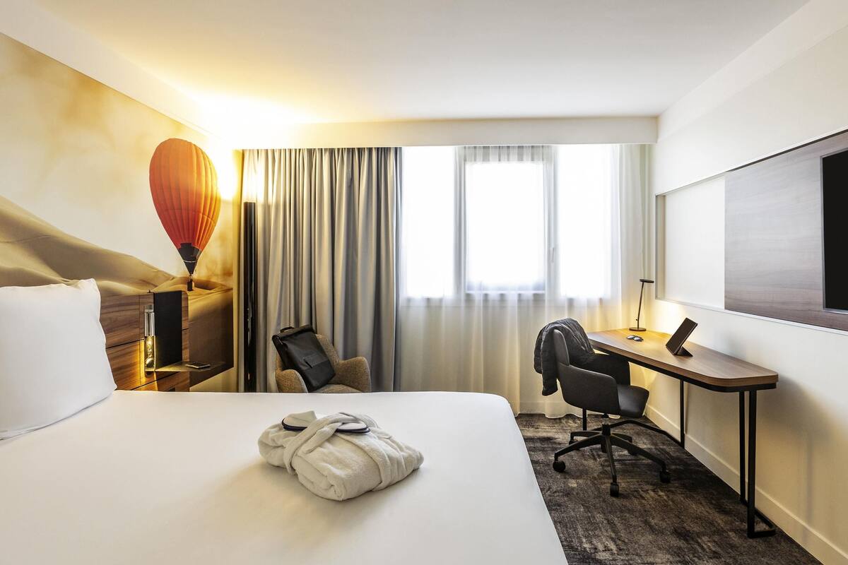 Ein Hotelzimmer mit Bett, Schreibtisch, Stuhl, Fernseher und einer Heißluftballon-Dekoration.