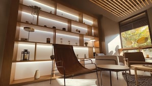 A modern living room with a brown leather chair, a round table, and a bookshelf with decorative items. - Novotel Bordeaux Centre Gare Saint Jean (Bordeaux)