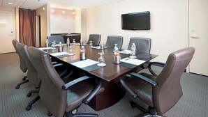 A conference room with a long table, six chairs, water bottles, and a flat-screen TV on the wall. - Crowne Plaza San Antonio Airport by IHG (San Antonio)