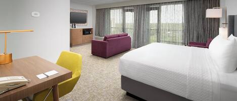 Habitación de hotel con cama, escritorio con teléfono, silla, televisor y ventana con cortinas.