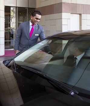 A man in a suit exiting a car with tinted windows.