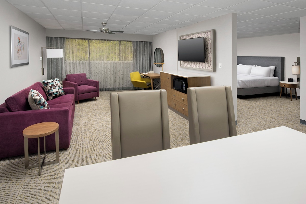 A hotel room with a bed, a sofa, a desk, and a TV.