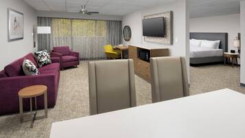 A hotel room with a bed, a sofa, a desk, and a TV.