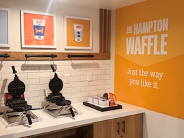 Una encimera de cocina con tres máquinas para hacer gofres, una cafetera y un letrero que dice "The Hampton Waffle".