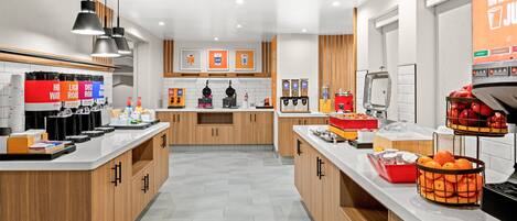 Una cocina moderna con armarios de madera, una isla central y diferentes estaciones de comida.
