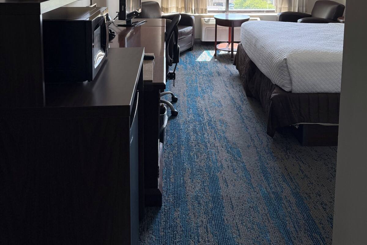 Una habitación de hotel con cama, escritorio, silla y vistas al exterior.