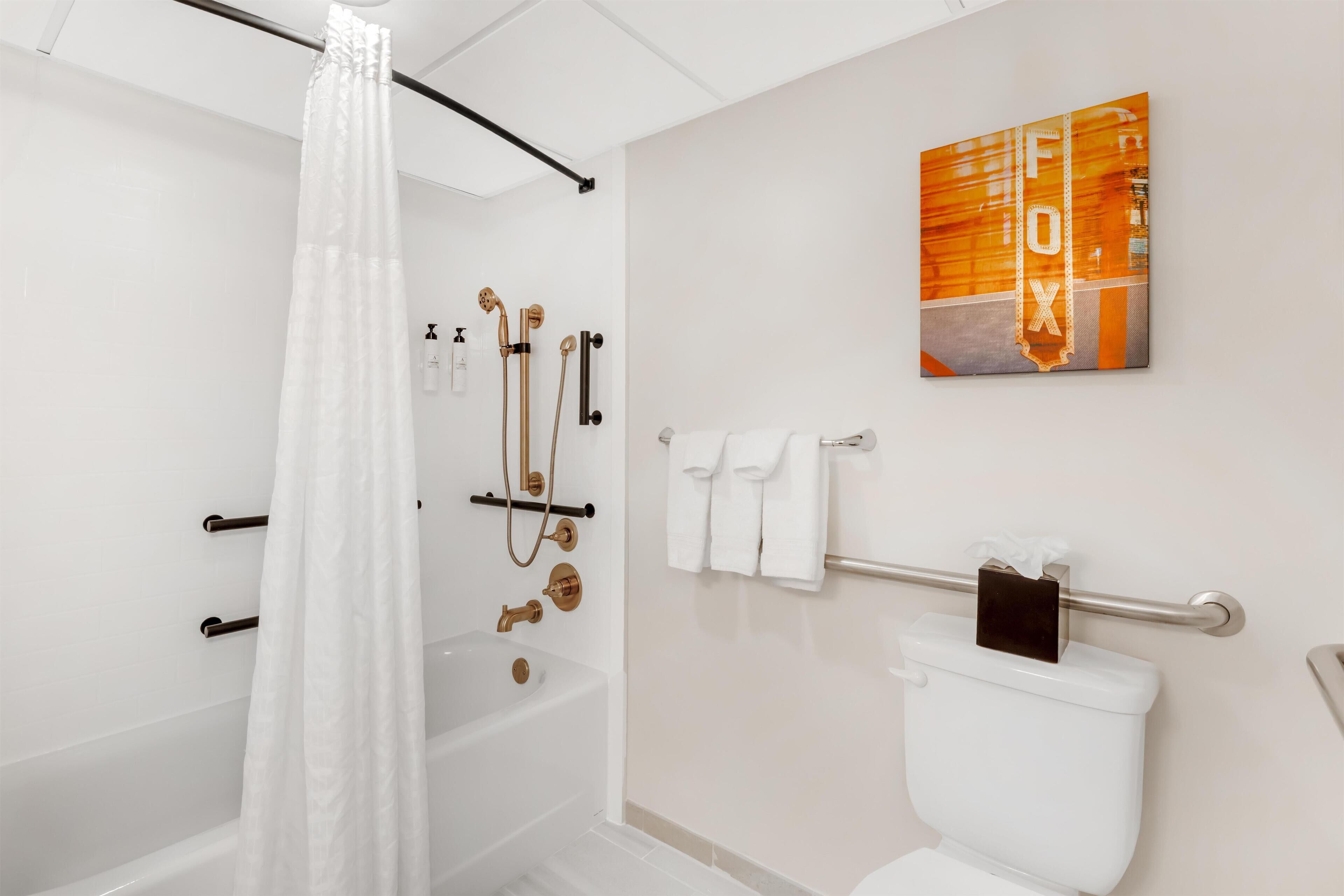 A modern bathroom with a bathtub, shower, and toilet.